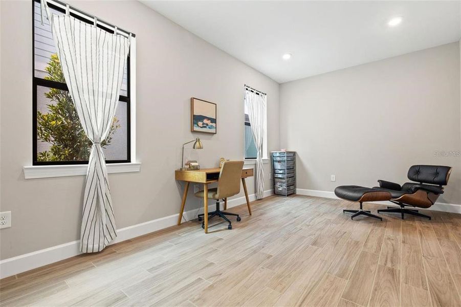 The office/den on the main level has wood-look plank tile flooring and recessed lighting.