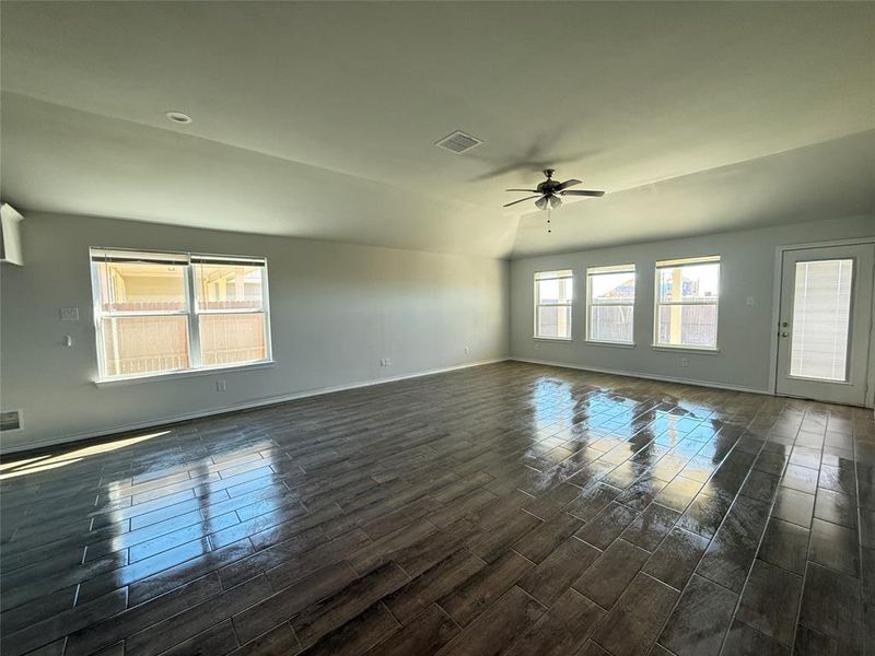 Unfurnished room featuring dark hardwood / wood-style floors, vaulted ceiling, plenty of natural light, and ceiling fan