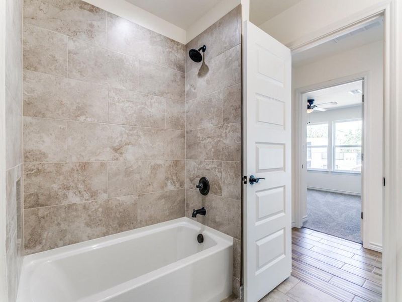 Bathroom featuring tiled shower / bath combo and ceiling fan