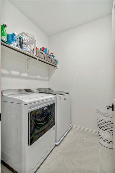Washroom featuring washing machine and clothes dryer and light tile floors