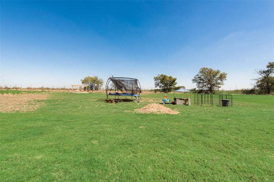 View of yard with a trampoline and a rural view