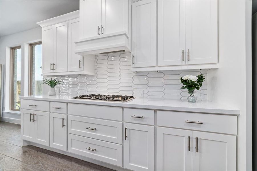 Beautiful White Cabinetry with sleek hardware, a 5 Burner gas cooktop, and a distinctive classic tile backsplash.