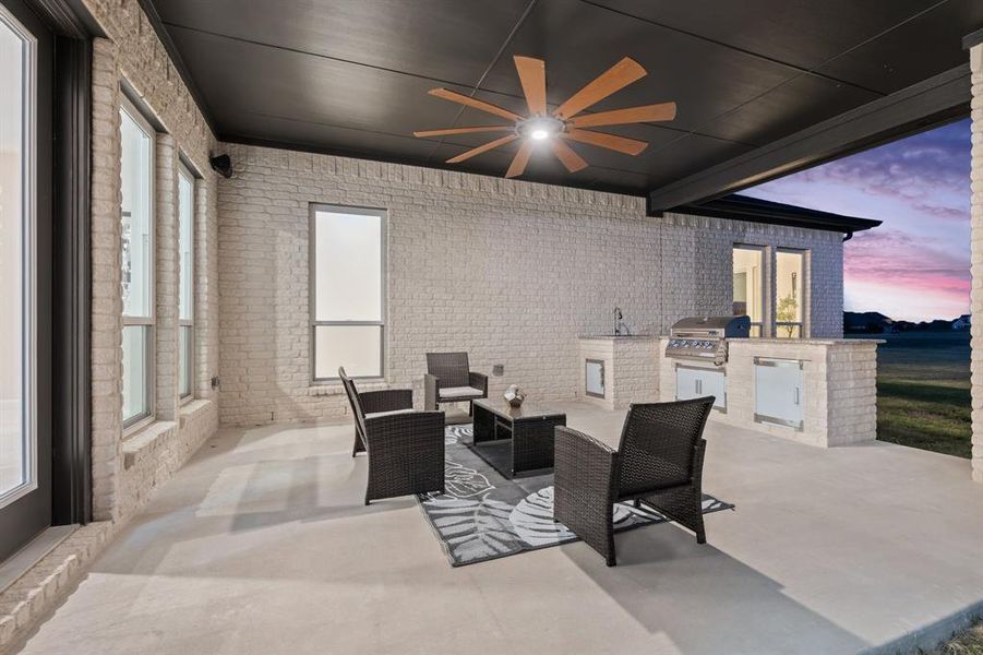 Patio terrace at dusk with ceiling fan, grilling area, an outdoor kitchen, and sink