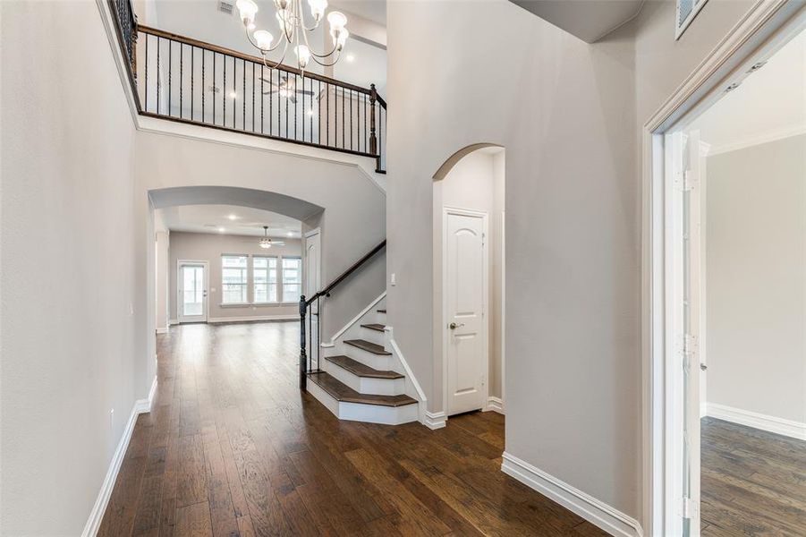 Foyer featuring ornamental molding, dark hardwood / wood-style floors, a towering ceiling, and a notable chandelier