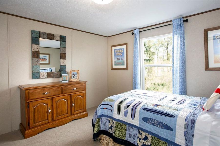 Carpeted bedroom with ornamental molding and a textured ceiling