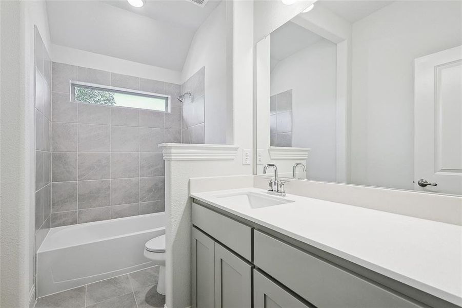 Full bathroom featuring vanity, toilet, tile patterned floors, and tiled shower / bath