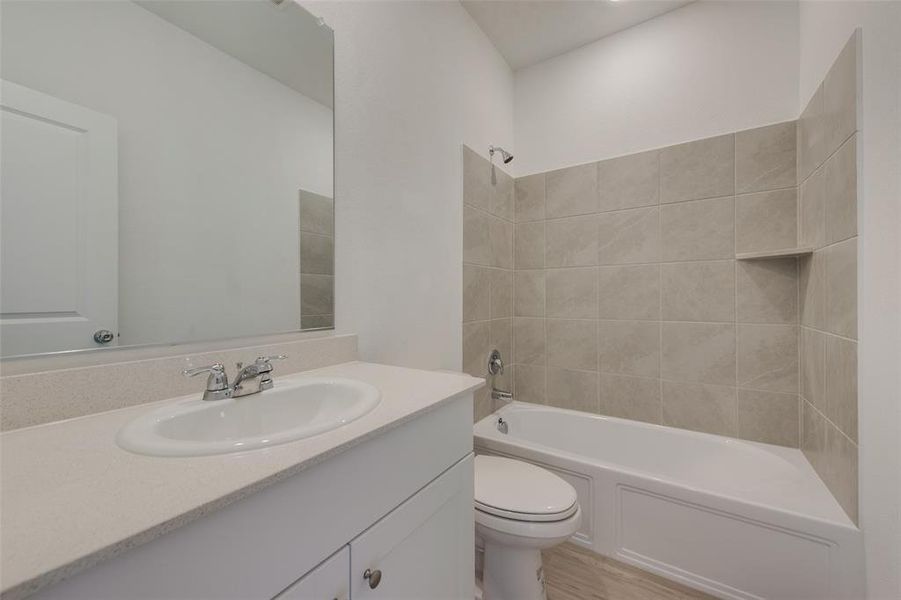 Full bathroom with vanity, tiled shower / bath, wood-type flooring, and toilet