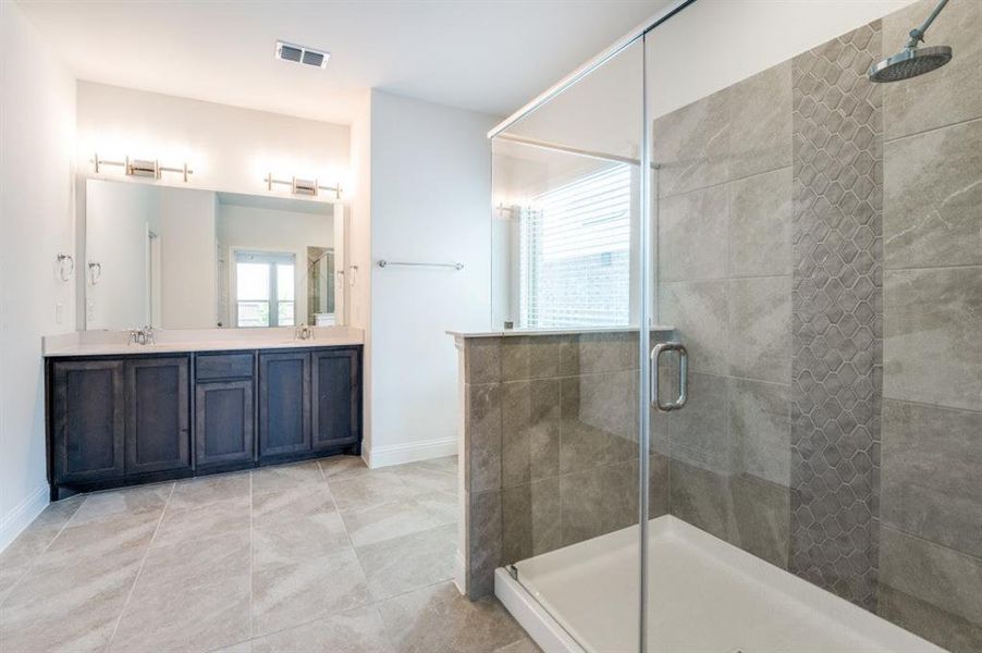Bathroom with walk in shower, double sink, tile floors, and large vanity
