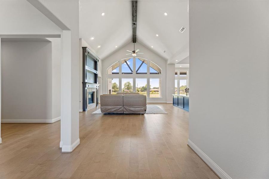 Living room with high vaulted ceiling, beamed ceiling, ceiling fan, and light hardwood / wood-style flooring