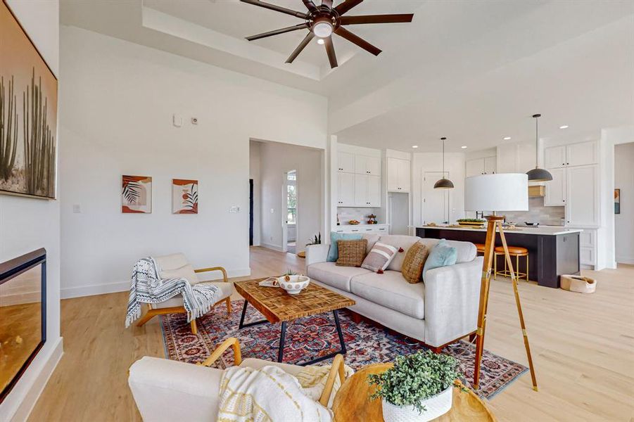 Living room with a towering ceiling, ceiling fan, and light hardwood / wood-style flooring