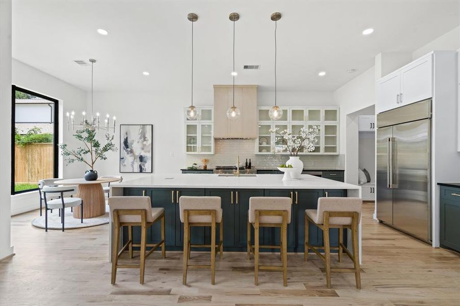 Stunning kitchen featuring oak floors, custom cabinets, a quartz island with seating, and expansive glass doors offering a lush backyard view.