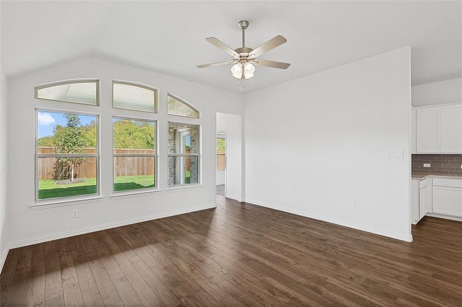 Unfurnished living room with dark wood-type flooring, ceiling fan, and vaulted ceiling