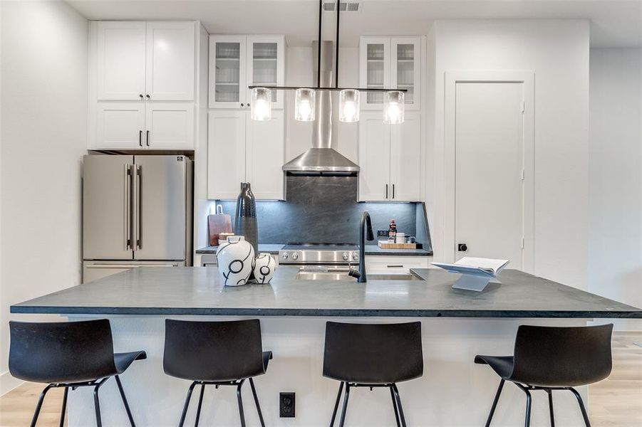 Kitchen featuring a large island with sink, light hardwood / wood-style floors, white cabinetry, and premium appliances