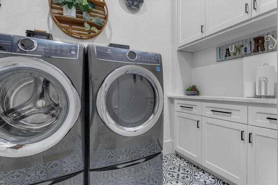 Clothes washing area featuring washing machine and dryer and cabinets