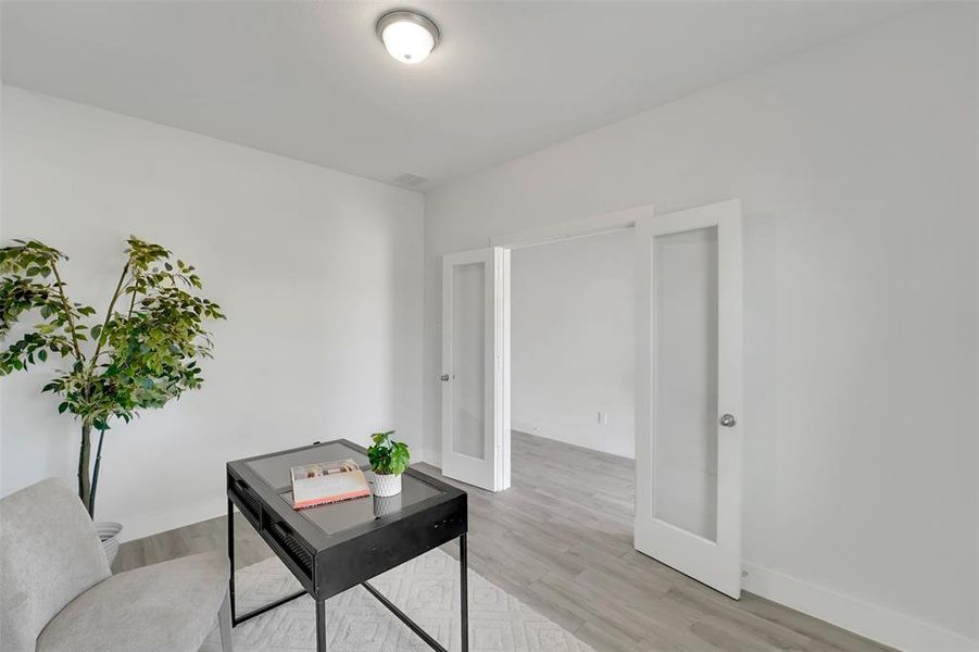 Office area with french doors and light hardwood / wood-style flooring