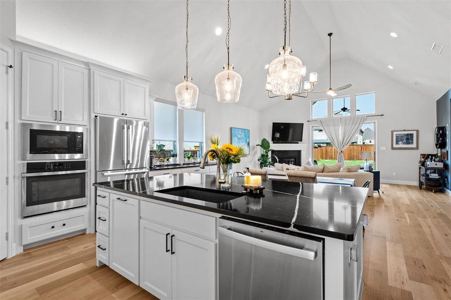 Kitchen featuring light hardwood / wood-style flooring, appliances with stainless steel finishes, a kitchen island with sink, white cabinets, and sink