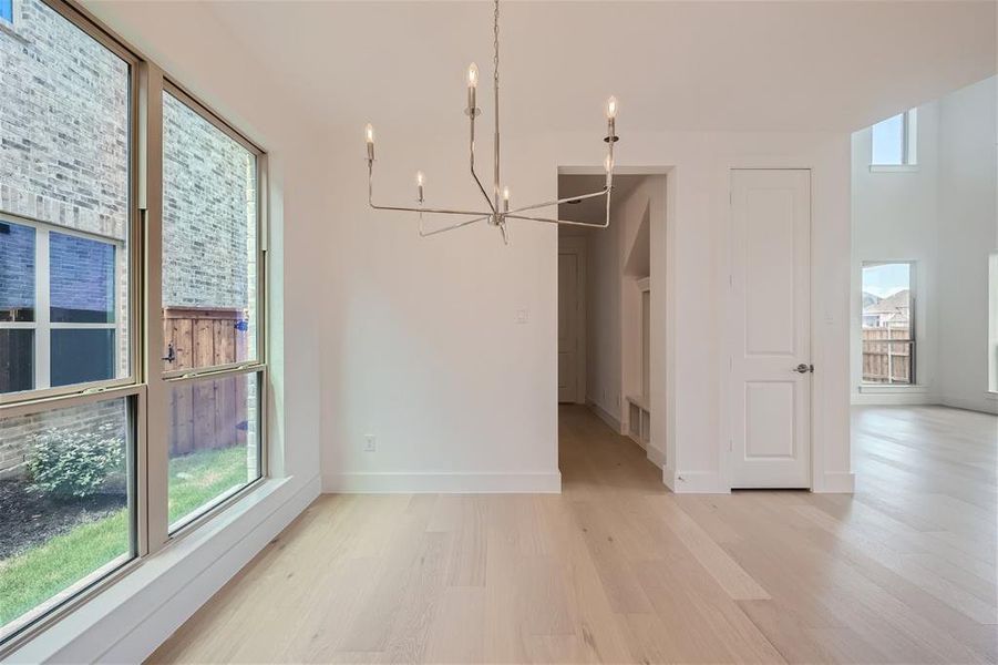 Casual dining area with light wood-type flooring, a chandelier, and a wealth of natural light