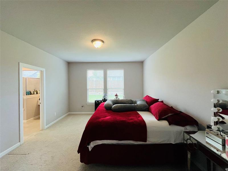 Bedroom featuring light carpet and ensuite bathroom