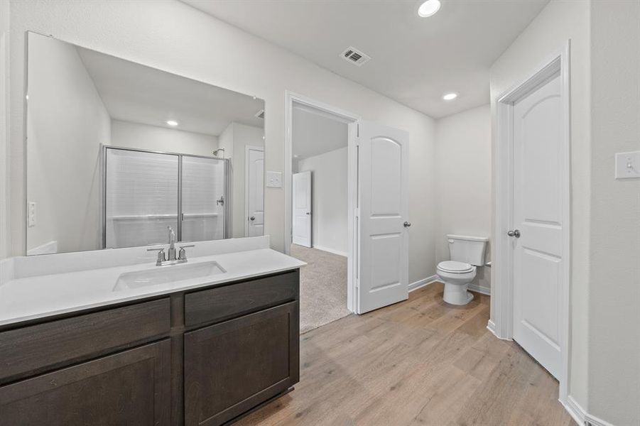 Bathroom with a shower with door, vanity, toilet, and hardwood / wood-style flooring