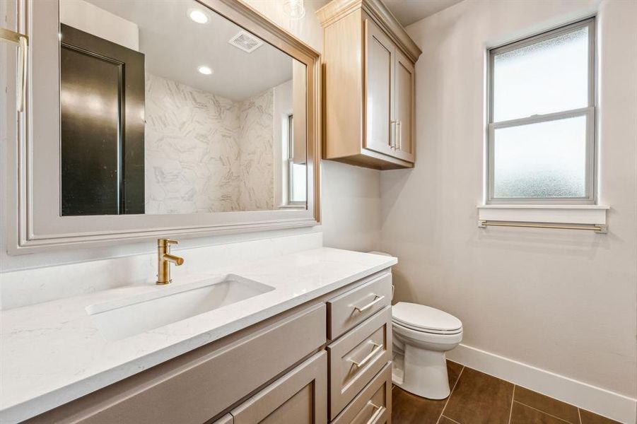 Bathroom with a healthy amount of sunlight, vanity, tile patterned flooring, and toilet