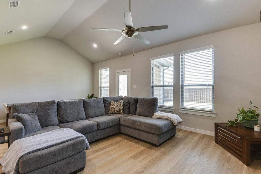 The living room has vaulted ceilings and light flooring.