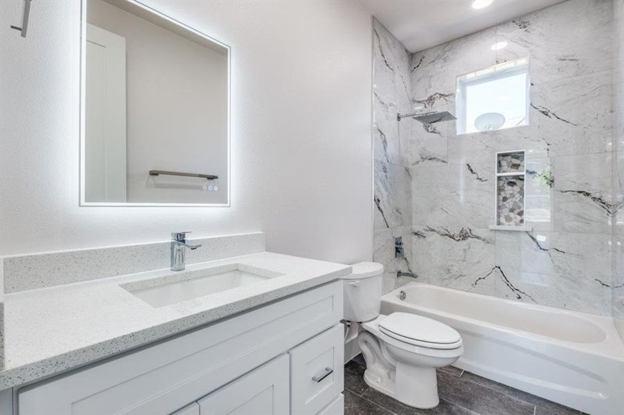 Full bathroom featuring tile flooring, vanity, toilet, and tiled shower / bath combo