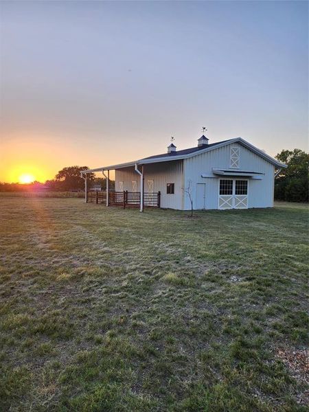 Back house at dusk with an outdoor structure and a yard