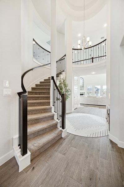 Welcome home! This elegant entryway features a sweeping staircase with dark railings, high ceilings, a gorgeous chandelier!