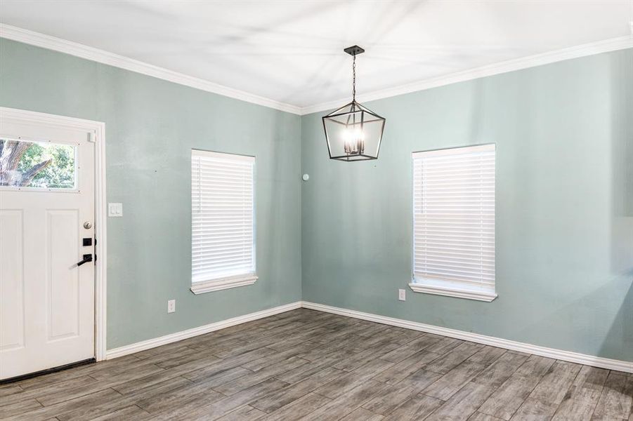 Foyer with ornamental molding, a chandelier, and hardwood / wood-style floors