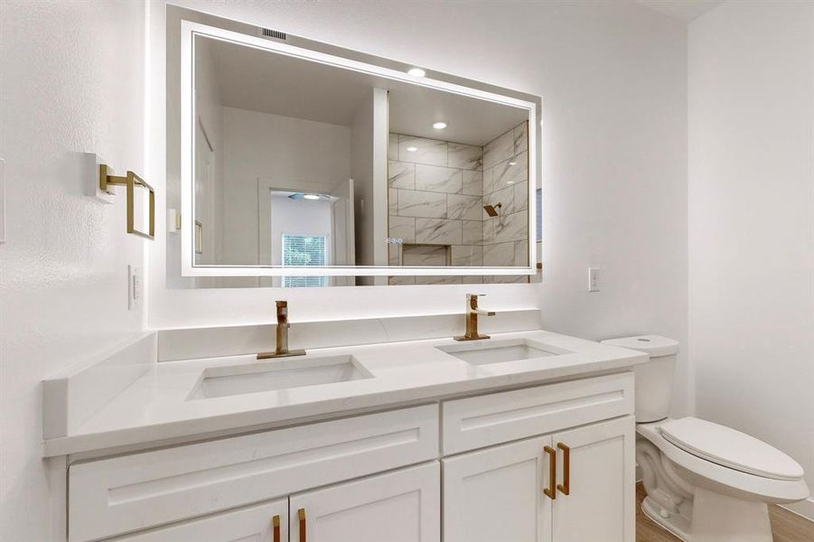 Bathroom with toilet, vanity, wood-type flooring, and tiled shower