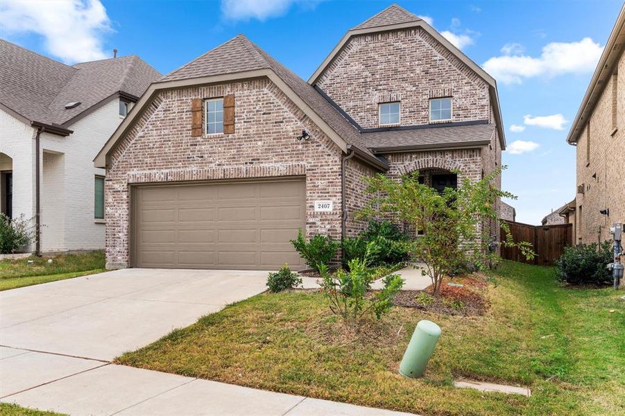 View of front of property featuring a front lawn and a garage