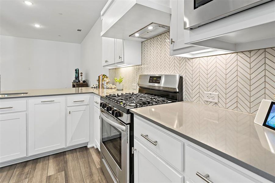 Kitchen featuring stainless steel gas stove, white cabinetry, dark hardwood / wood-style flooring, and premium range hood