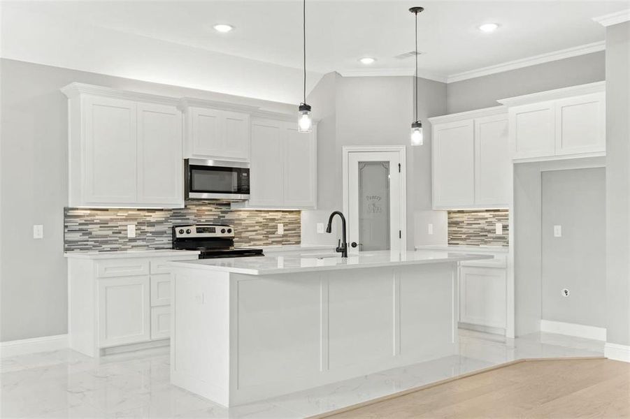 Kitchen with appliances with stainless steel finishes, white cabinetry, an island with sink, and hanging light fixtures