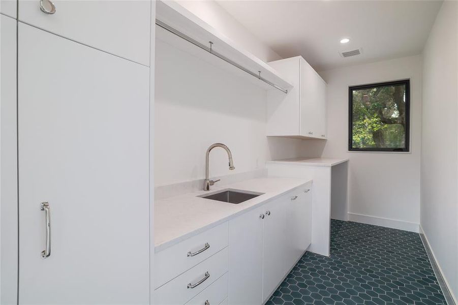 The second floor laundry room sits between the primary bedroom and the secondary bedrooms, where a majority of laundry would be generated. Designed for a side-by-side washer and dryer, it features two countertops for folding and laundry prep, PLENTY of storage and a utility sink....