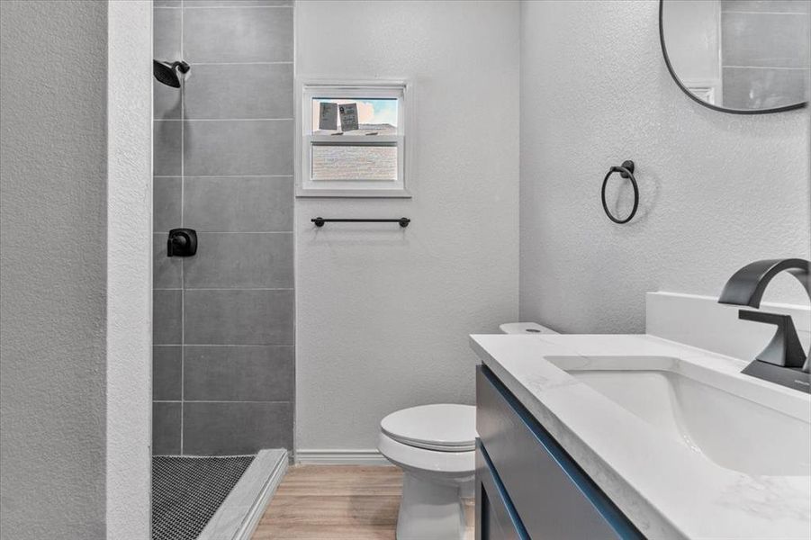 Bathroom featuring vanity, a tile shower, toilet, and hardwood / wood-style floors