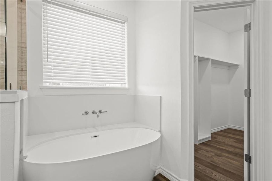 Bathroom with a wealth of natural light, wood-type flooring, and a tub