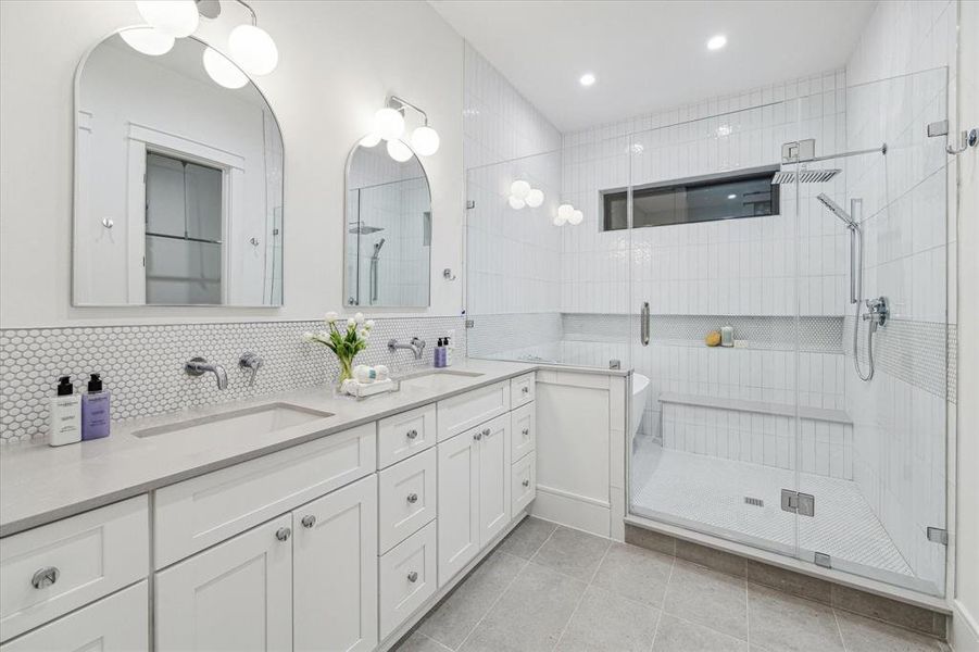 Primary Bath with a 12 x 24 Tile Floor, Shaker Style Cabinetry with Soft Close Drawers and Doors. Slab Quartz Counter, Penny Round Mosaic Tile Backsplash. Dual Rectangle Sinks, Widespread Bathroom Faucets in Chrome, Framed Mirrors and Dual Two Globe LED Vanity Lights in Chrome.