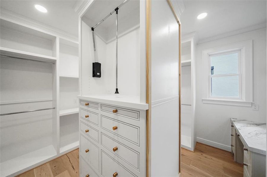Spacious primary suite closet with built-in shelves, drawers, and a marble vanity for makeup and hair. Features a large full-length mirror. Bright and elegant.