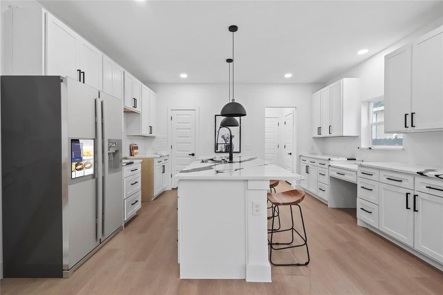 Kitchen featuring white cabinetry, stainless steel fridge with ice dispenser, sink, a center island, and light hardwood / wood-style floors