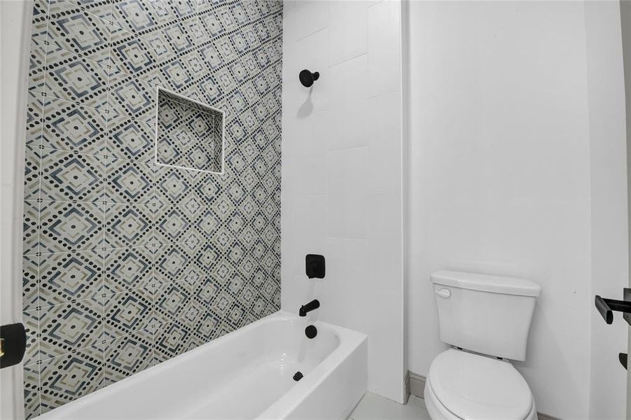 Bathroom featuring tiled shower / bath combo and toilet