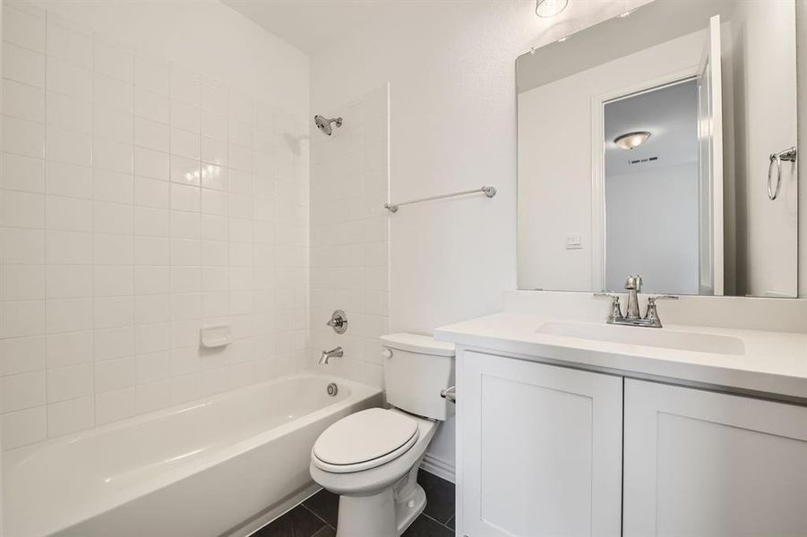 Full bathroom featuring vanity, tiled shower / bath combo, toilet, and tile patterned floors