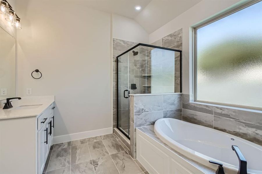 Bathroom featuring independent shower and bath, vanity, and vaulted ceiling