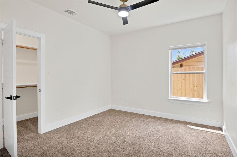 Carpeted empty room featuring ceiling fan and plenty of natural light