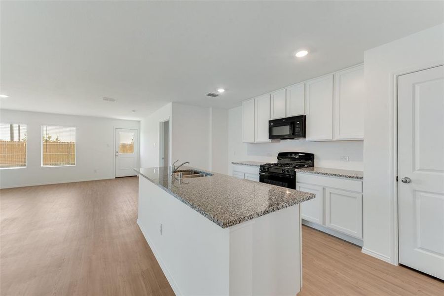 Kitchen featuring black appliances, sink, light wood-type flooring, and white cabinets