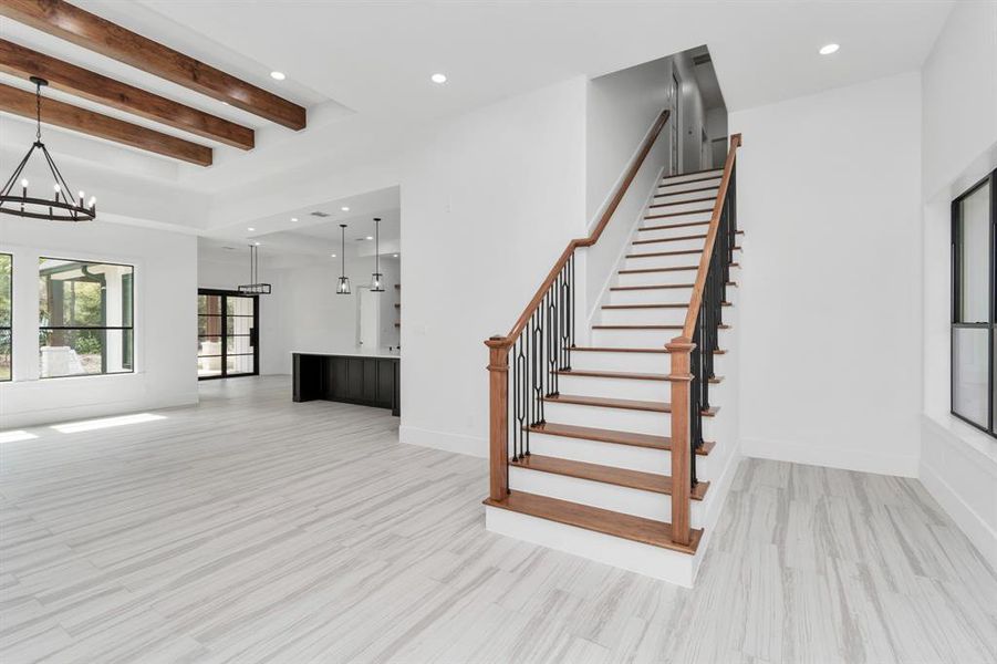 Another view of the home with ample natural light, and the open floor plan seamlessly connects to a kitchen with chic dark cabinetry and pendant lighting.