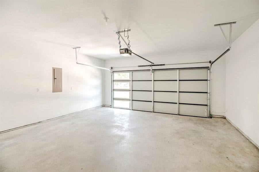 Garage featuring electric panel and a garage door opener