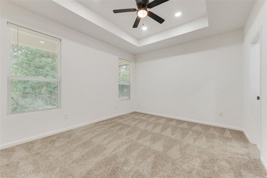 Unfurnished room with carpet flooring, a tray ceiling, and ceiling fan