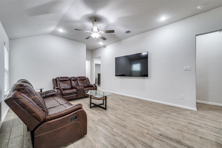 Living room featuring ceiling fan, light hardwood / wood-style flooring, and vaulted ceiling