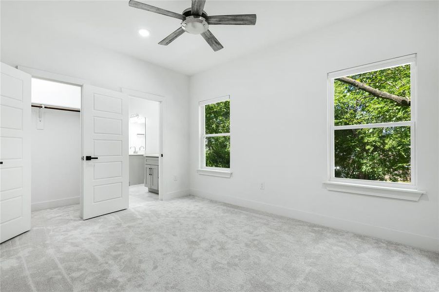 Unfurnished bedroom with ceiling fan, a closet, connected bathroom, and light carpet