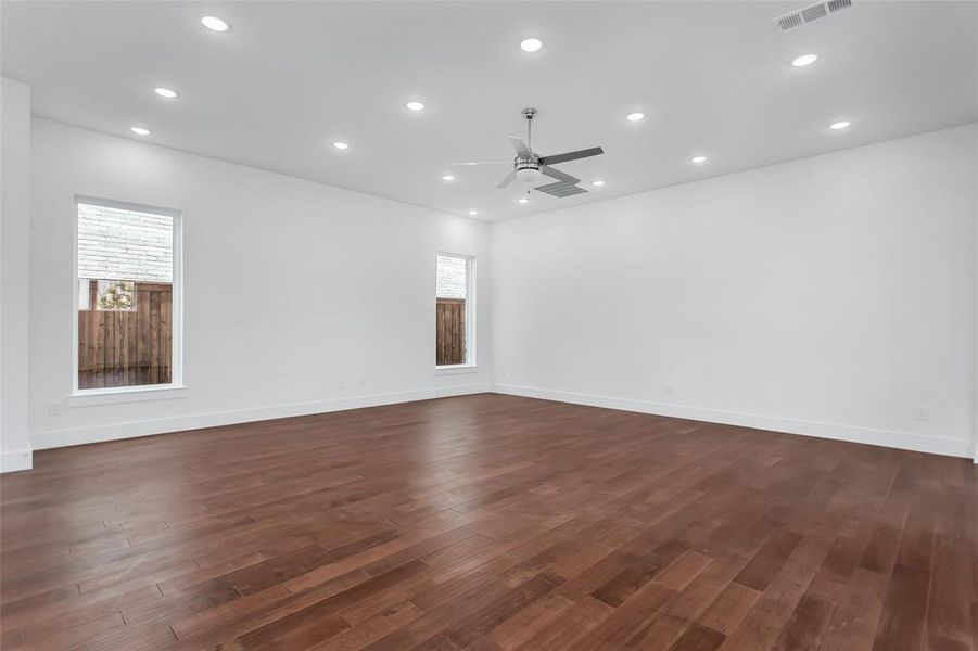 Unfurnished living room with plenty of natural light, dark wood-type flooring, and ceiling fan